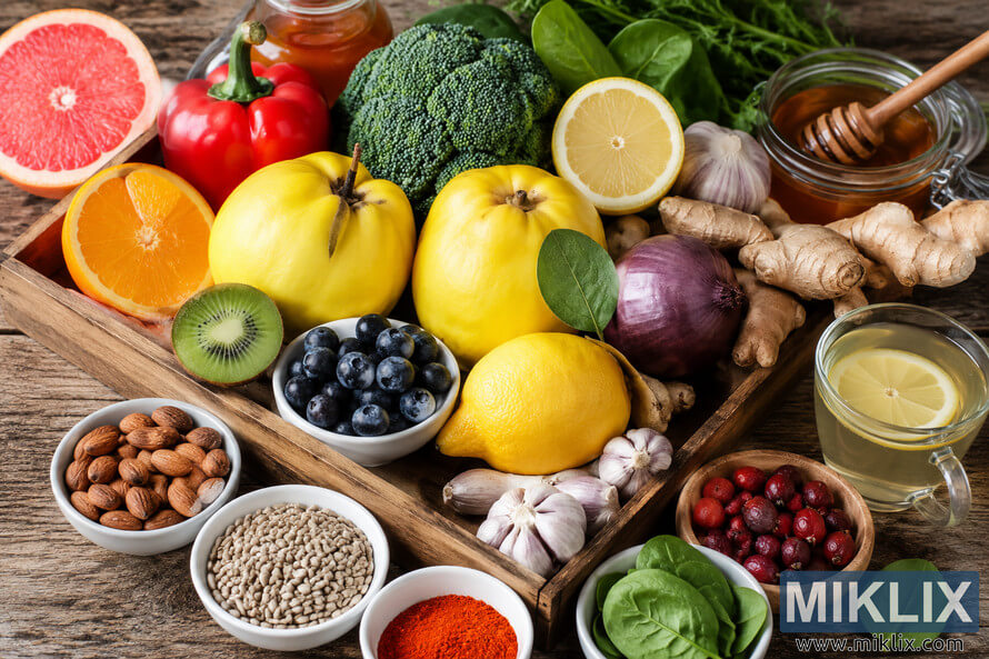 A vibrant arrangement of immune-boosting foods displayed on a rustic wooden surface, featuring fresh quinces, citrus fruits, broccoli, garlic, ginger, blueberries, almonds, spinach, honey, and seeds in natural light. A vibrant arrangement of immune-boosting foods displayed on a rustic wooden surface, featuring fresh quinces, citrus fruits, broccoli, garlic, ginger, blueberries, almonds, spinach, honey, and seeds in natural light.