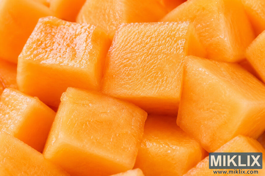 Macro close-up of freshly cut cantaloupe cubes showing vibrant orange flesh, juicy texture, and soft natural highlights in a tightly cropped landscape composition. Macro close-up of freshly cut cantaloupe cubes showing vibrant orange flesh, juicy texture, and soft natural highlights in a tightly cropped landscape composition.