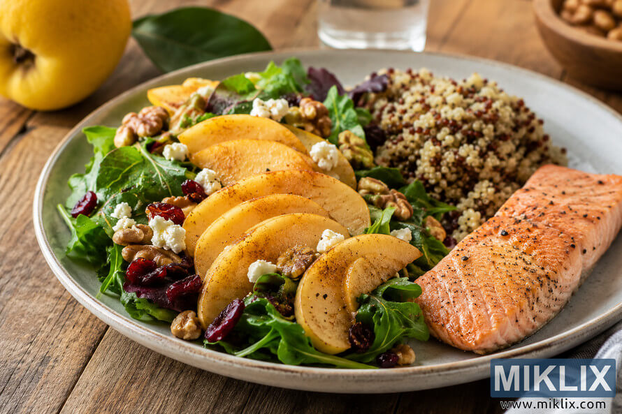 A heart-healthy meal featuring sliced quince on a fresh green salad with walnuts, cranberries, feta cheese, quinoa, and grilled salmon served on a rustic wooden table in warm natural light. A heart-healthy meal featuring sliced quince on a fresh green salad with walnuts, cranberries, feta cheese, quinoa, and grilled salmon served on a rustic wooden table in warm natural light.