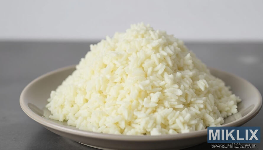 Close-up de um prato de arroz de couve-flor branco e fofo sobre um fundo neutro.