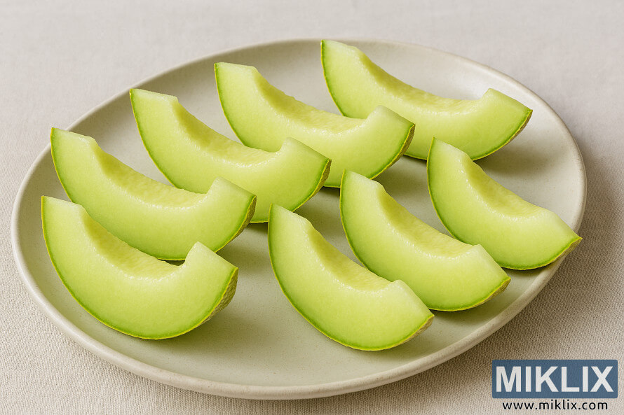 Neatly arranged honeydew melon slices on a ceramic serving platter Neatly arranged honeydew melon slices on a ceramic serving platter