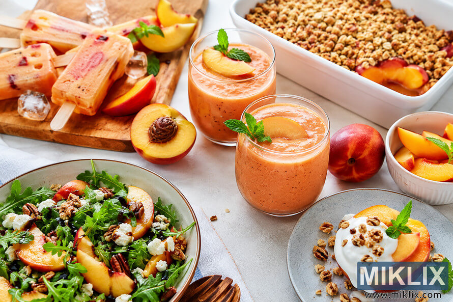 A vibrant high-resolution food photography scene featuring creative nectarine dishes including creamy smoothies garnished with fresh nectarine slices and mint, a fresh arugula salad topped with nectarines, nuts, and cheese, homemade fruit popsicles, baked nectarine crumble, and yogurt dessert plates arranged on a rustic table in natural light. A vibrant high-resolution food photography scene featuring creative nectarine dishes including creamy smoothies garnished with fresh nectarine slices and mint, a fresh arugula salad topped with nectarines, nuts, and cheese, homemade fruit popsicles, baked nectarine crumble, and yogurt dessert plates arranged on a rustic table in natural light.