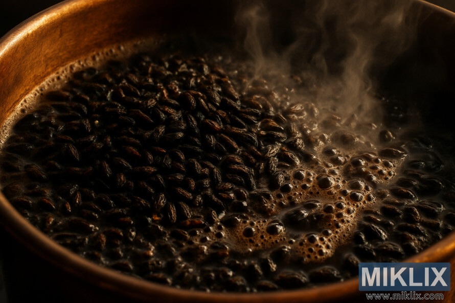 Prim-plan al boabelor de malÈ prÄjite care clocotesc Ã®ntr-un ceaun de cupru sub o luminÄ caldÄ de culoarea chihlimbarului.