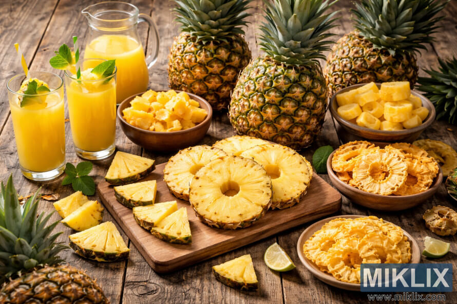 Fotografia d'alta resoluciÃ³ de pinyes senceres, rodanxes fresques, anelles seques i suc de pinya disposades sobre una taula de fusta rÃºstica amb menta i llima.