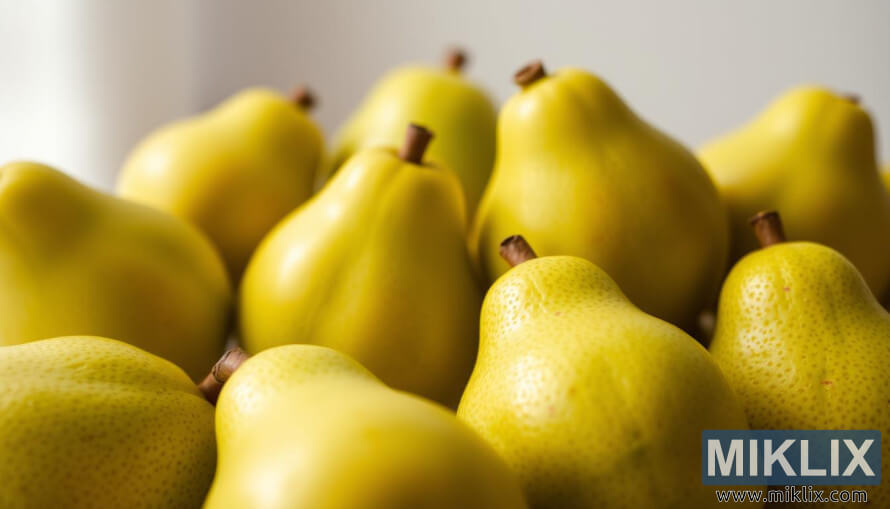 Detail zralÃ½ch guav se zelenou slupkou a rÅ¯Å¾ovÃ½m odstÃ­nem na mÄkkÃ©m rozmazanÃ©m pozadÃ­ za pÅirozenÃ©ho svÄtla.