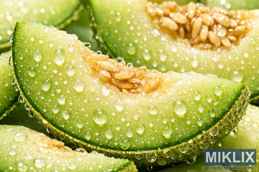 Close-up of fresh honeydew melon slices covered in glistening water droplets, highlighting the juicy texture and vibrant green rind. Close-up of fresh honeydew melon slices covered in glistening water droplets, highlighting the juicy texture and vibrant green rind.