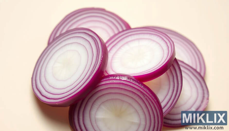 Close-up of sliced red and white onions arranged in overlapping layers on a light background. Close-up of sliced red and white onions arranged in overlapping layers on a light background.