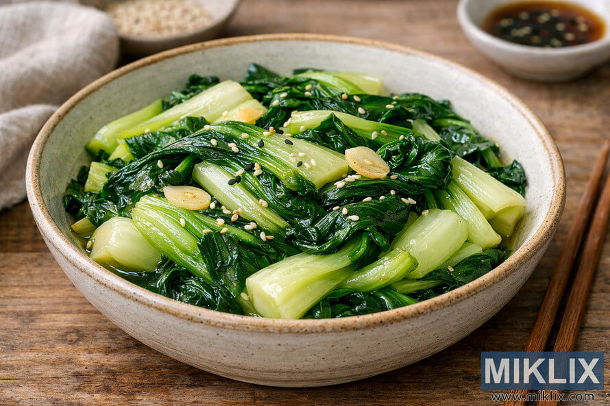 A rustic ceramic bowl filled with gently cooked bok choy, garnished with sesame seeds and golden garlic slices, placed on a wooden surface with chopsticks and a linen cloth nearby. A rustic ceramic bowl filled with gently cooked bok choy, garnished with sesame seeds and golden garlic slices, placed on a wooden surface with chopsticks and a linen cloth nearby.