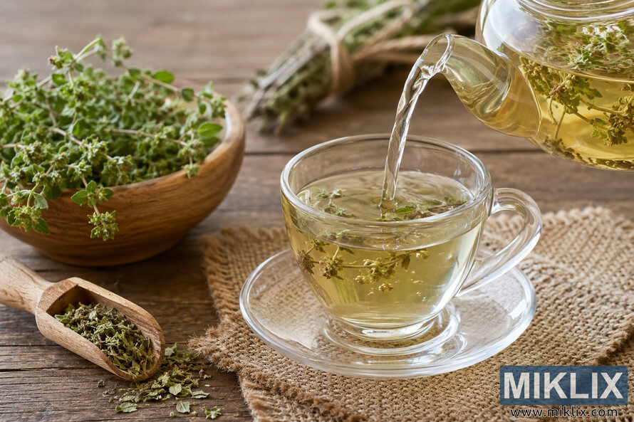 A rustic kitchen scene showing marjoram tea being poured from a clear glass teapot into a transparent teacup on a burlap cloth, surrounded by fresh and dried marjoram herbs, wooden utensils, and warm natural lighting. A rustic kitchen scene showing marjoram tea being poured from a clear glass teapot into a transparent teacup on a burlap cloth, surrounded by fresh and dried marjoram herbs, wooden utensils, and warm natural lighting.