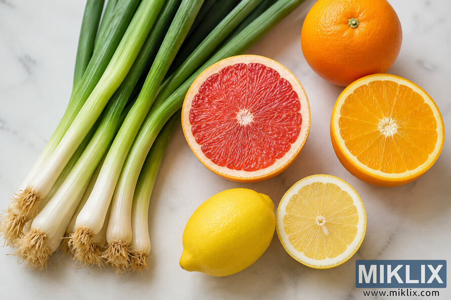 Overhead landscape image of fresh scallions, grapefruit, oranges, and lemon arranged on a light marble surface to represent a healthy immune system and natural wellness. Overhead landscape image of fresh scallions, grapefruit, oranges, and lemon arranged on a light marble surface to represent a healthy immune system and natural wellness.