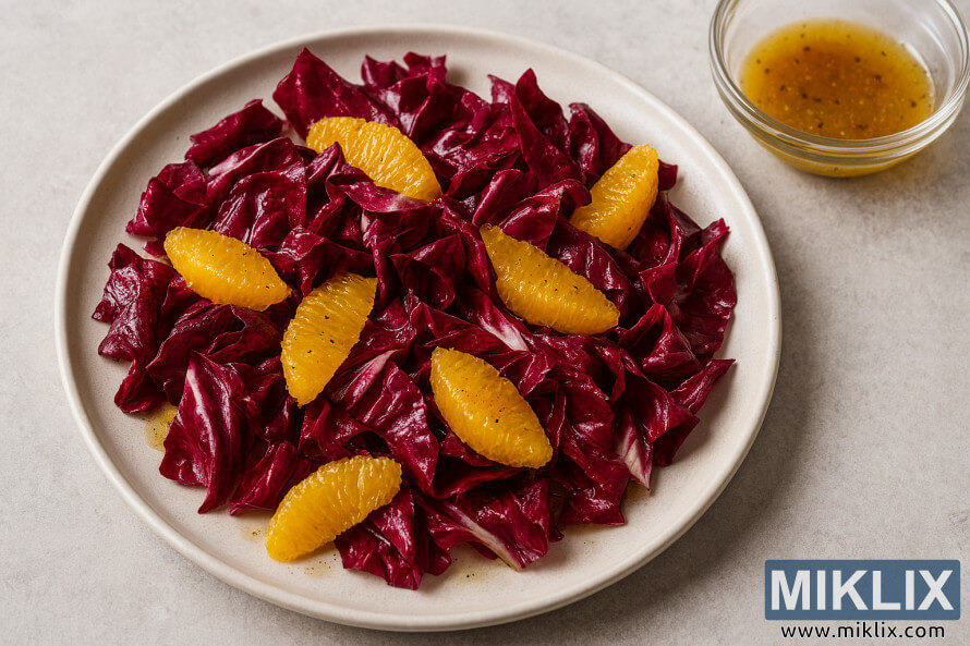 Landscape photo of a radicchio salad with orange segments and vinaigrette in a ceramic bowl